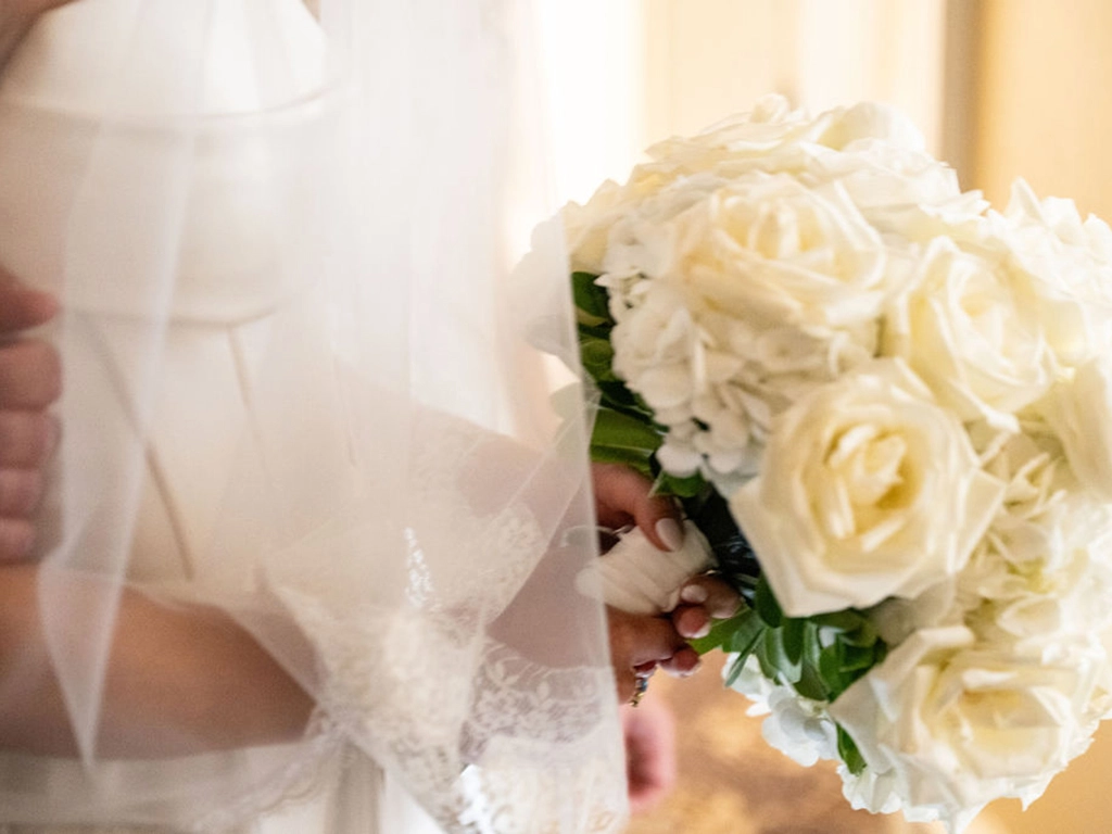 Close-up of a bride holding a white rose bouquet beneath her veil