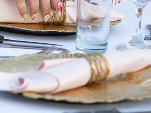 A blush napkin placed on a gold charger at a reception table